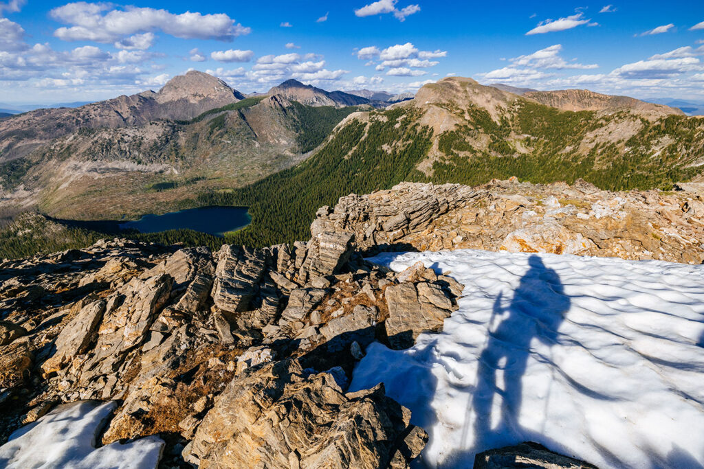 Rocky alpine terrain in Montana with lingering snow patches and mountain lake views below