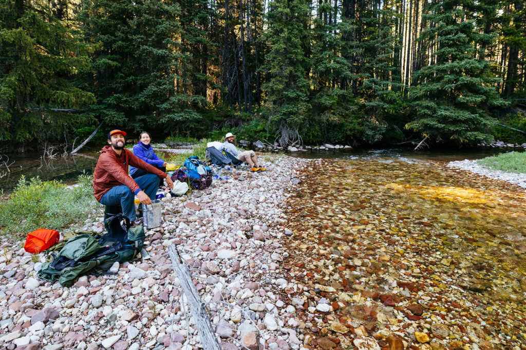 Backpackers relaxing beside Moose Creek during a backpacking trip through Montana's Bob Marshall Wilderness.
