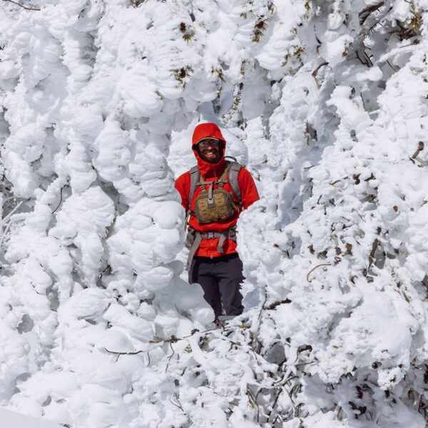 Mitch standing among trees covered in thick rime ice in Montana