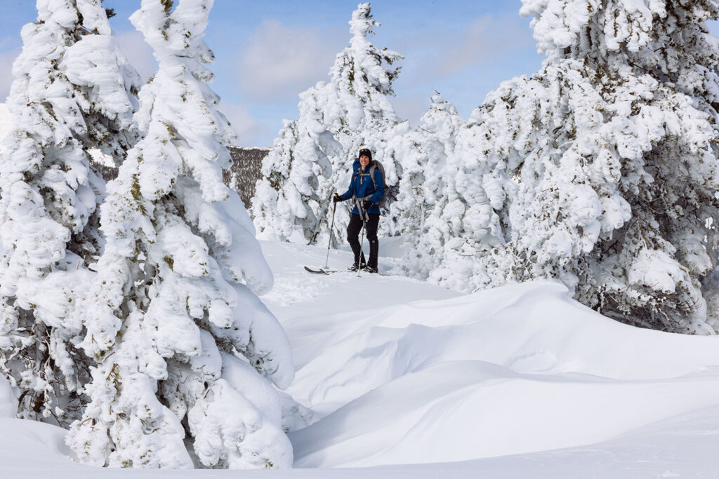 Valerie moving through snow-covered trees shaped by rime ice in a Montana winter landscape