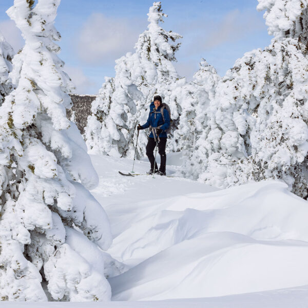 Valerie moving through snow-covered trees shaped by rime ice in a Montana winter landscape